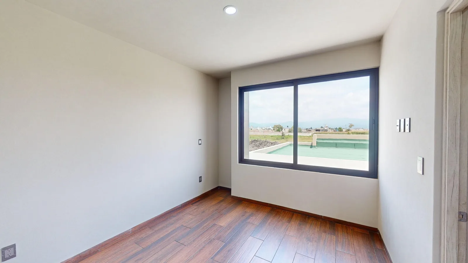 Recámara con piso de madera y ventana amplia