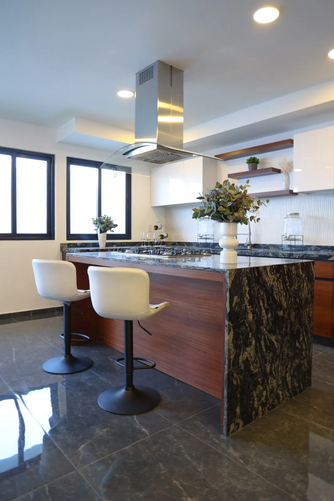 Cocina del Prototipo A en Villas Zacango con isla de granito oscuro, campana de acero y bancos altos
