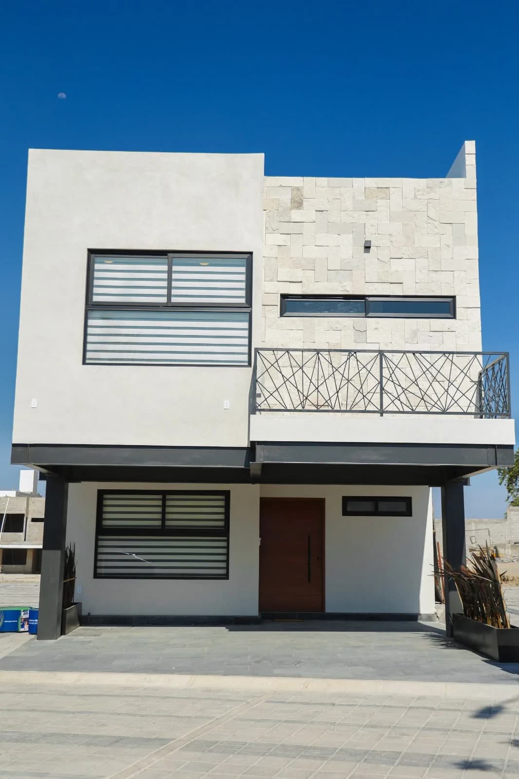 Fachada de una casa en Villas Zacango, Calimaya, con piedra, balcón de herrería y estacionamiento techado