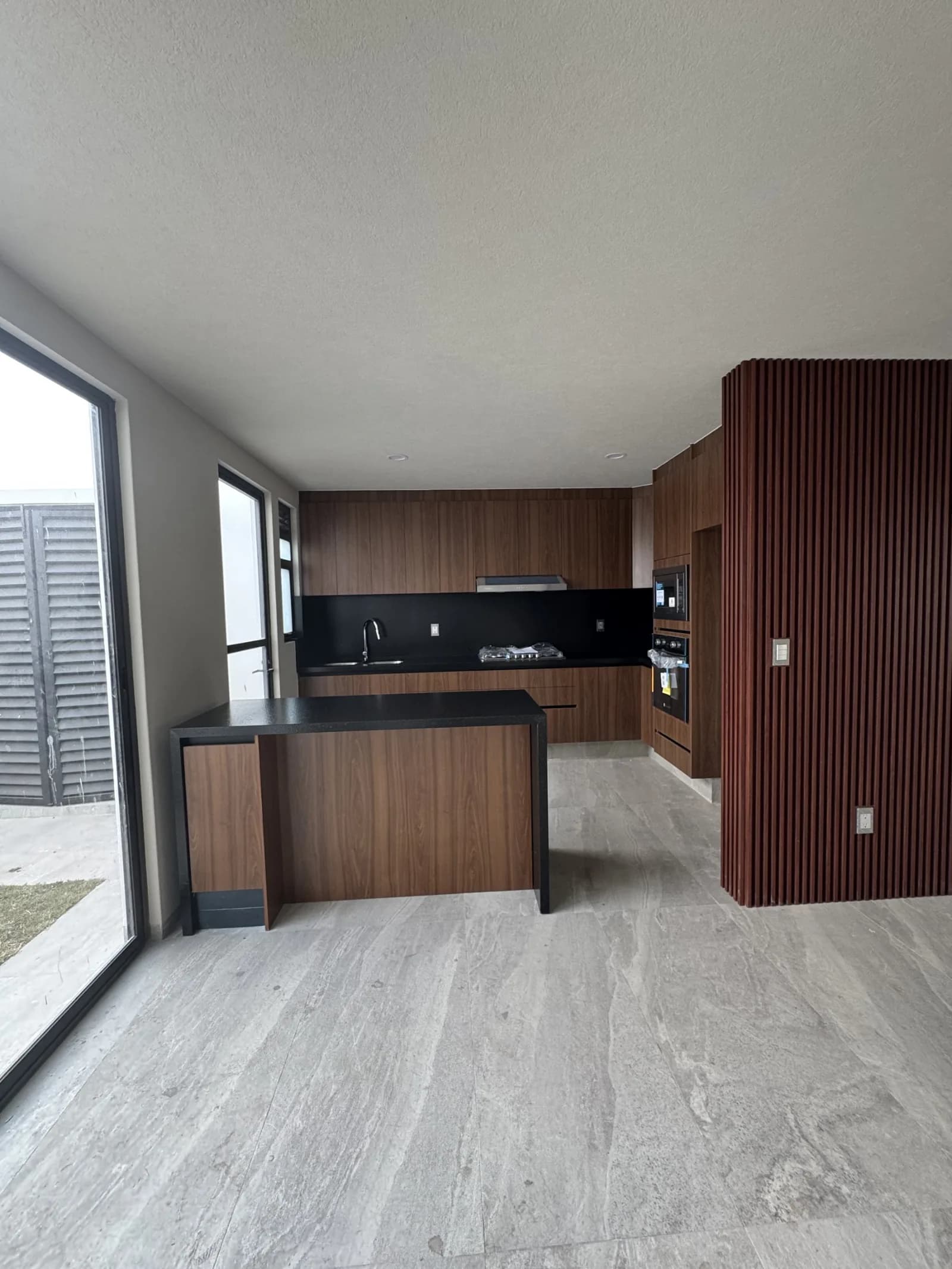 Cocina equipada con barra de granito y muro de madera en Esmeralda Residencial 14